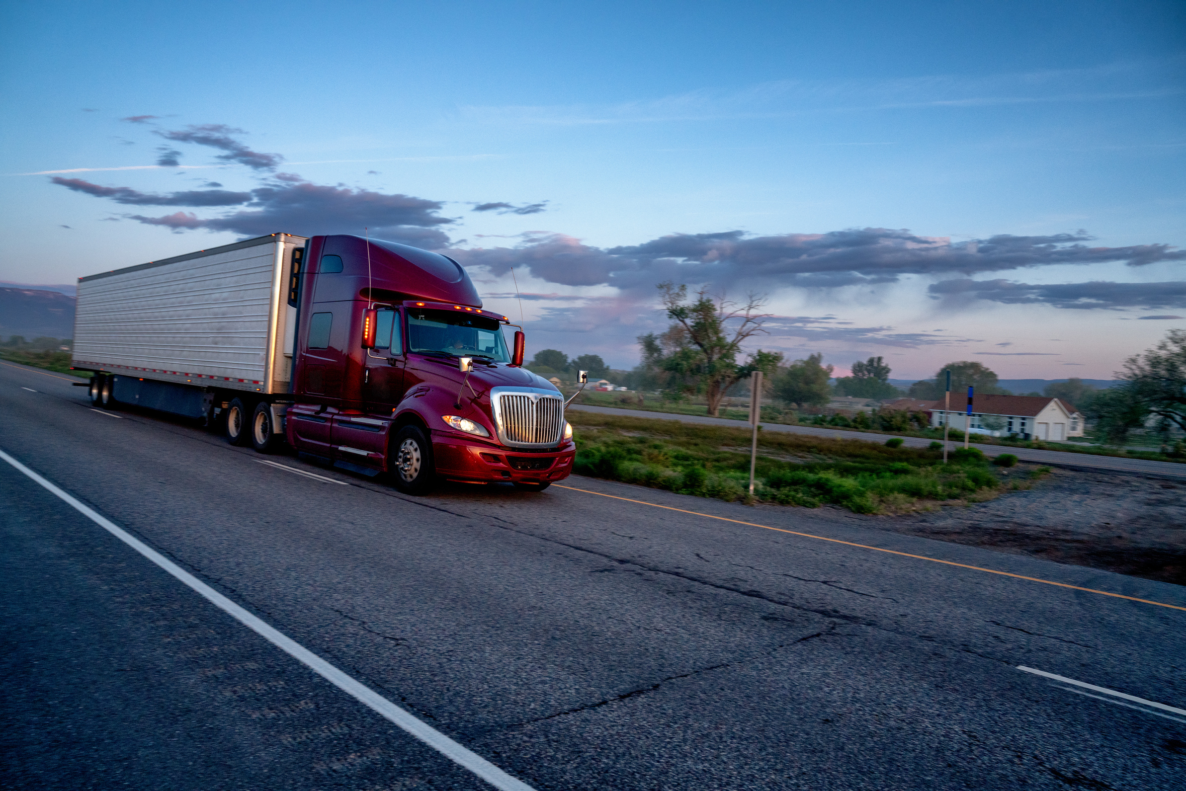 Long Haul Semi Truck on a Highway at Dusk under a Dramatic Sky